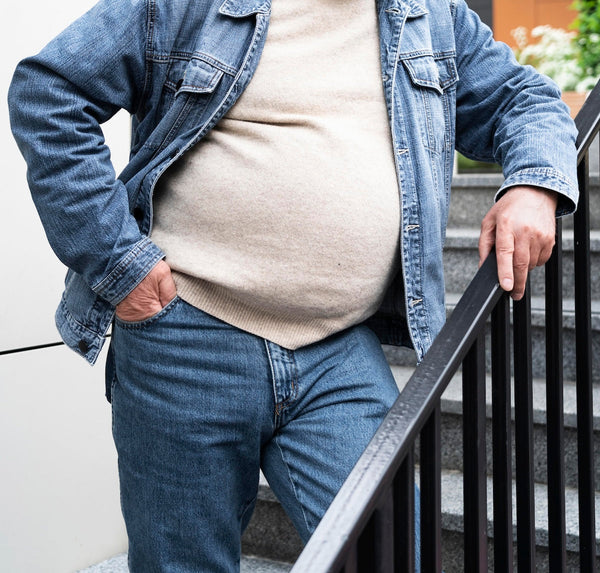 Un homme avec du ventre qui porte un pull et un jean